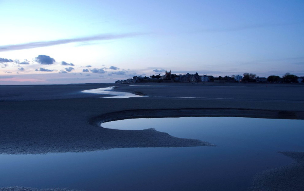 Vue crépusculaire de l'Estran de la Baie de Somme et les reflets sur les étendues d'eau qui sillonnent jusqu'au Crotoy.